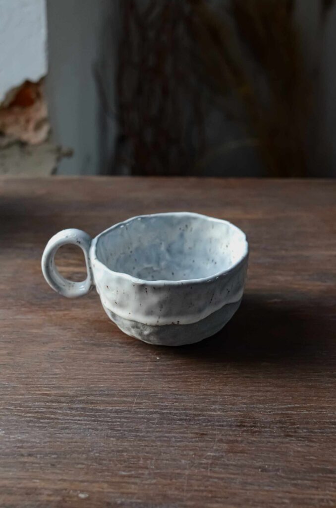 niebieska filiżanka ceramiczna z kamionki z białym szkliwem w rude piegi